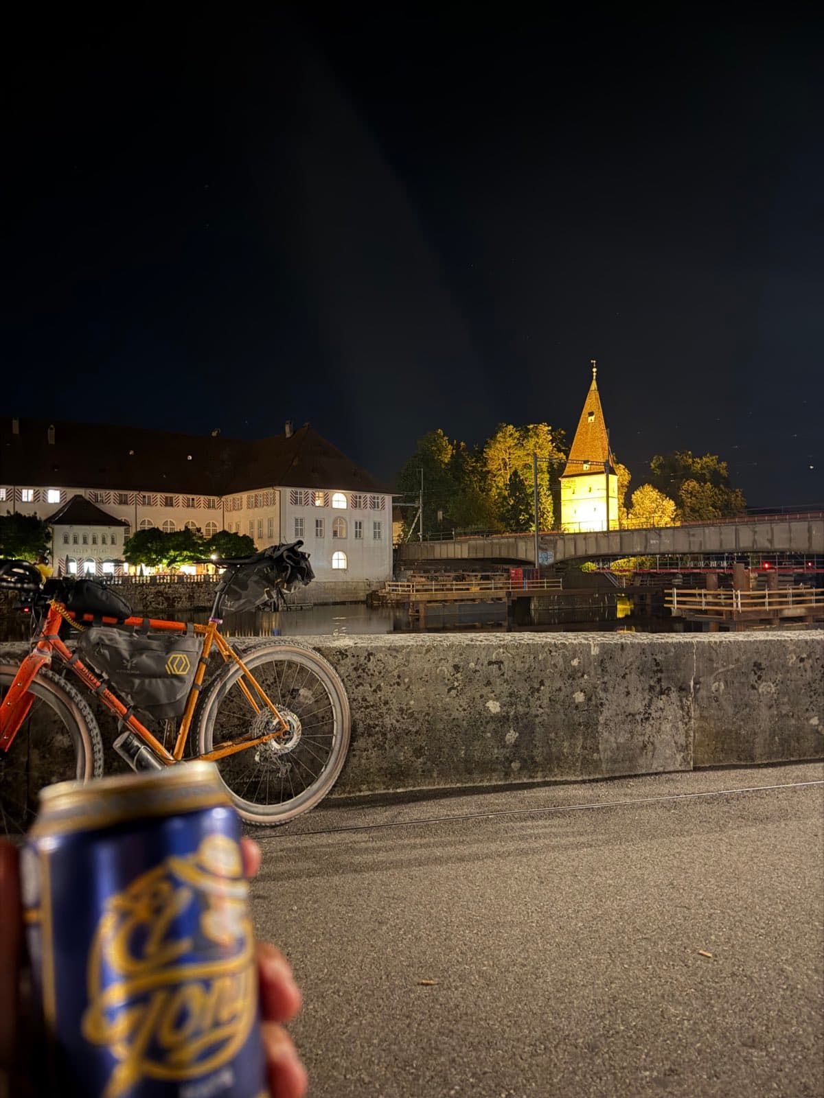 Bepacktes Gravelbike an einer Mauer an der Aare in Solothurn bei Nacht, im Hintergrund ein angestrahlter Turm