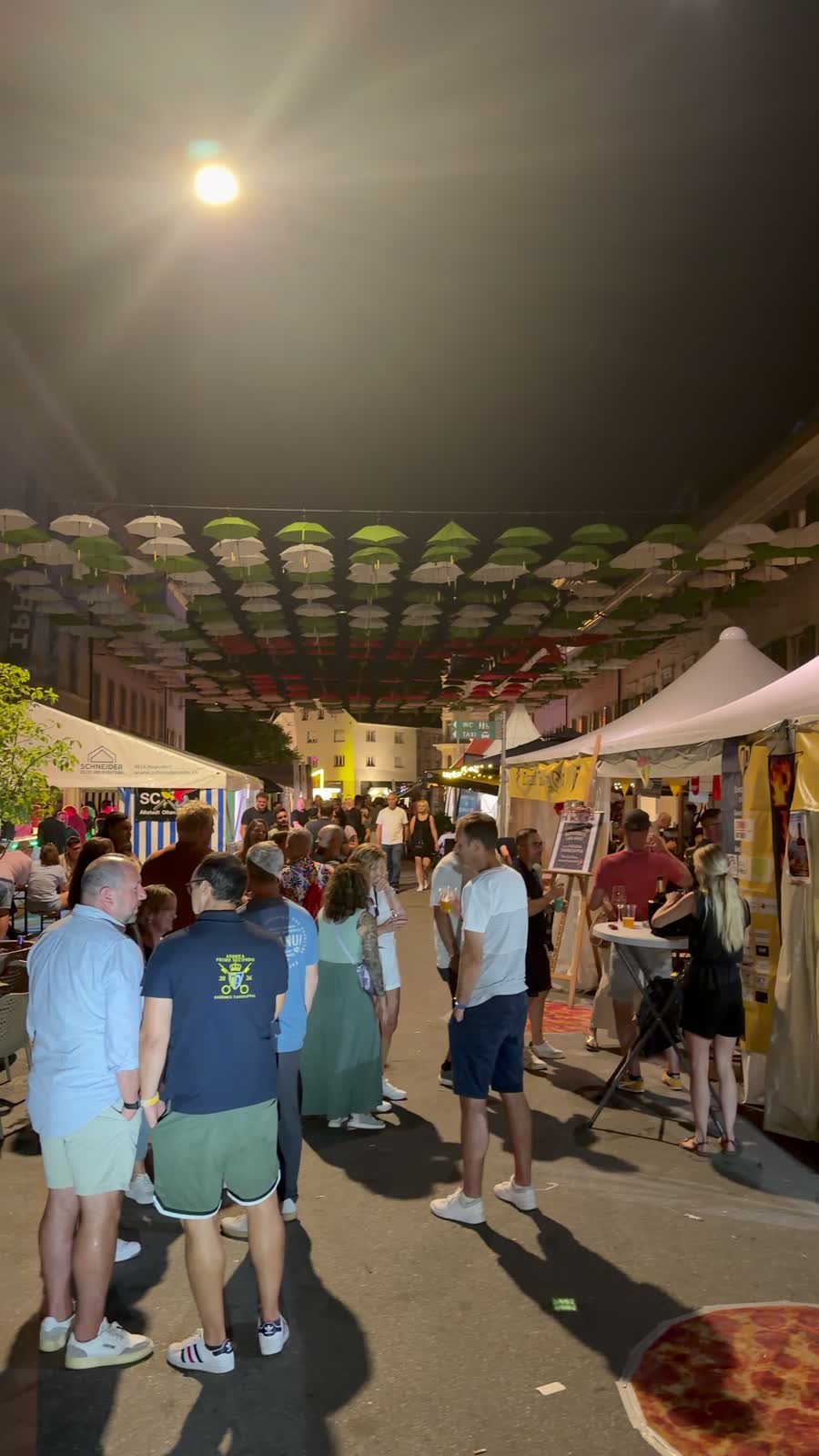 Nächtliches Strassenfest in Olten mit Ständen, Sonnenschirmen über der Gasse und vielen Menschen